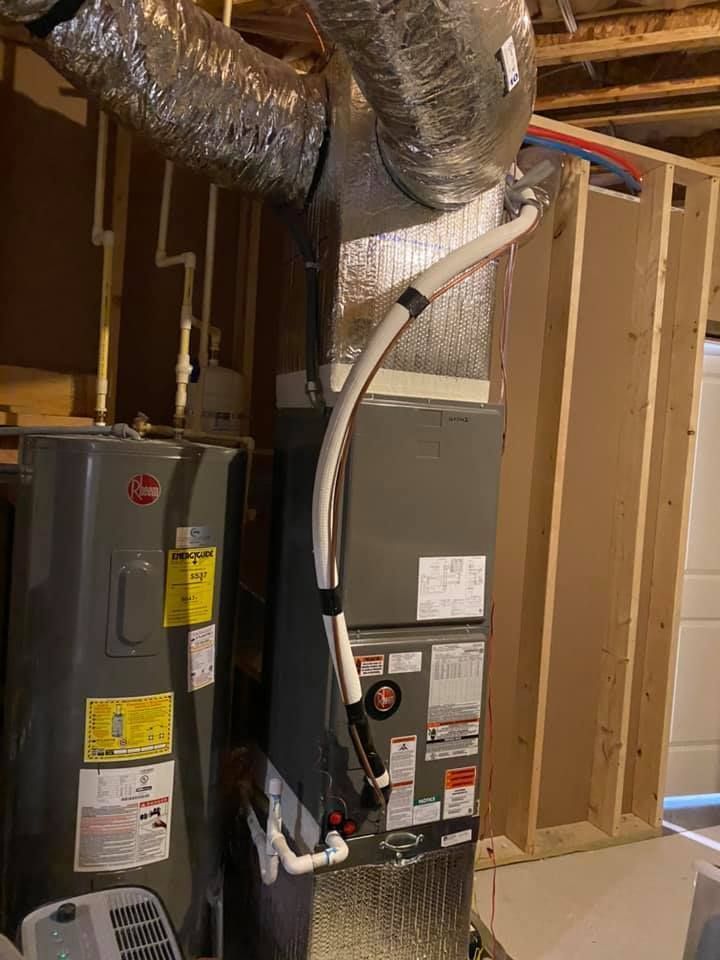 Basement HVAC equipment with metal ductwork and a gray furnace beside exposed wooden framing.