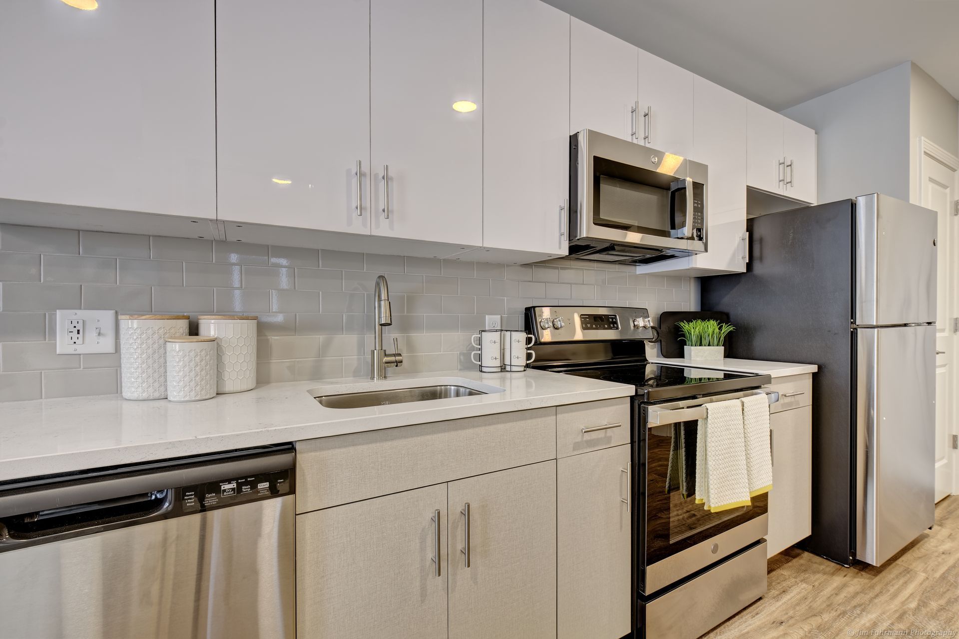 Modern kitchen with white cabinets, stainless steel appliances, and gray backsplash.