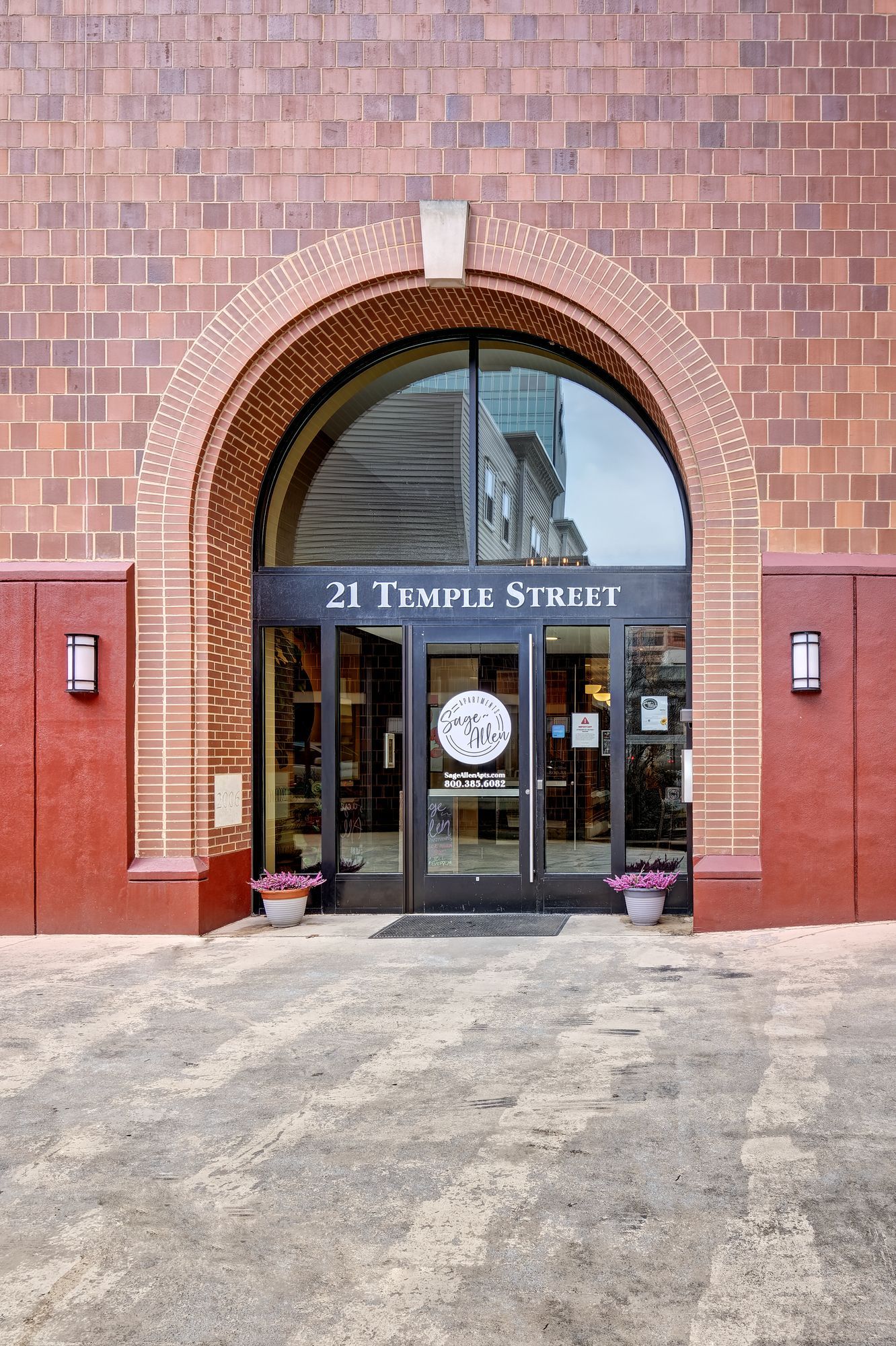 Entrance to 21 Temple Street, featuring a brick archway and glass doors. A sign is above the entrance with the address.