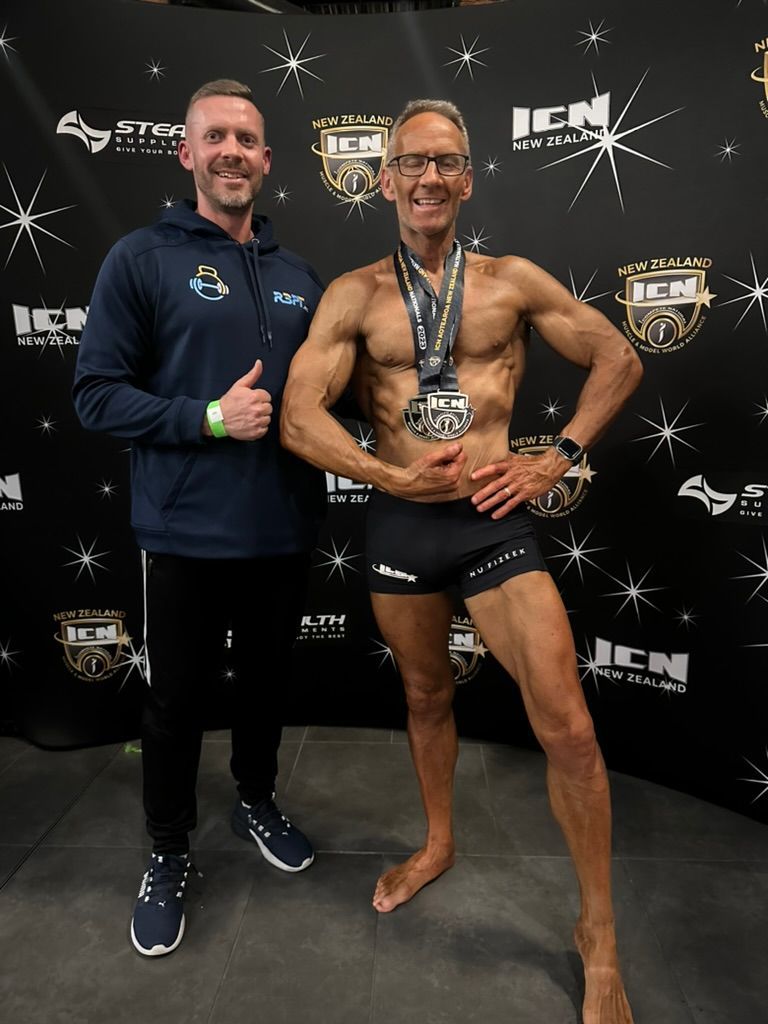 Ray and client Ken are posing for a picture in front of a banner that says icn new zealand