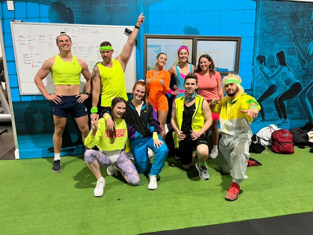 Ray and a group of people are posing for a picture in a gym.