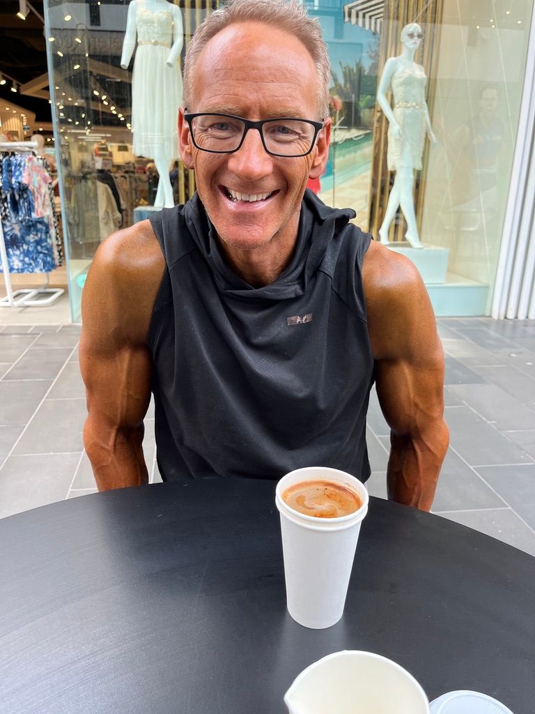 Key man is sitting at a table with a cup of coffee.