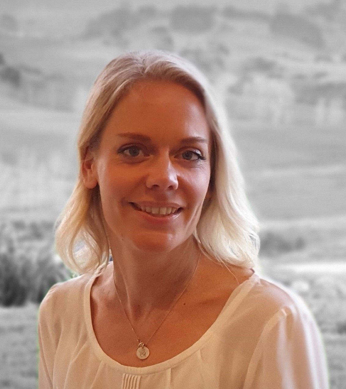 Anna from Nourished for Success wearing a white shirt and a necklace smiles for the camera