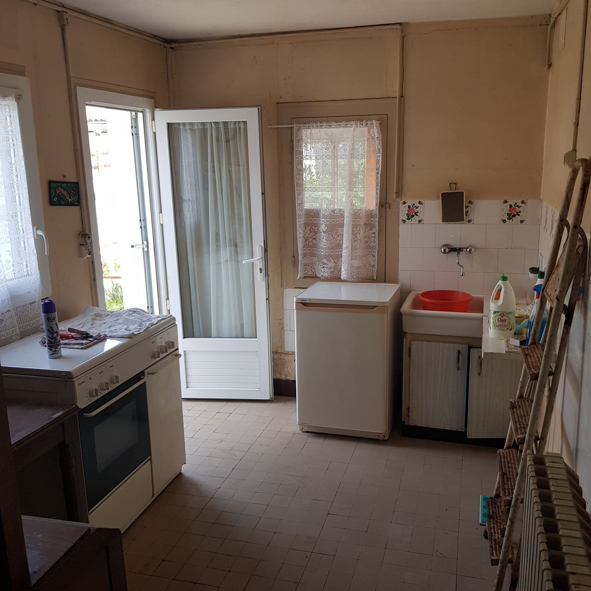 kitchen before renovation with an old fridge, porcelain sink and an old gas cooker