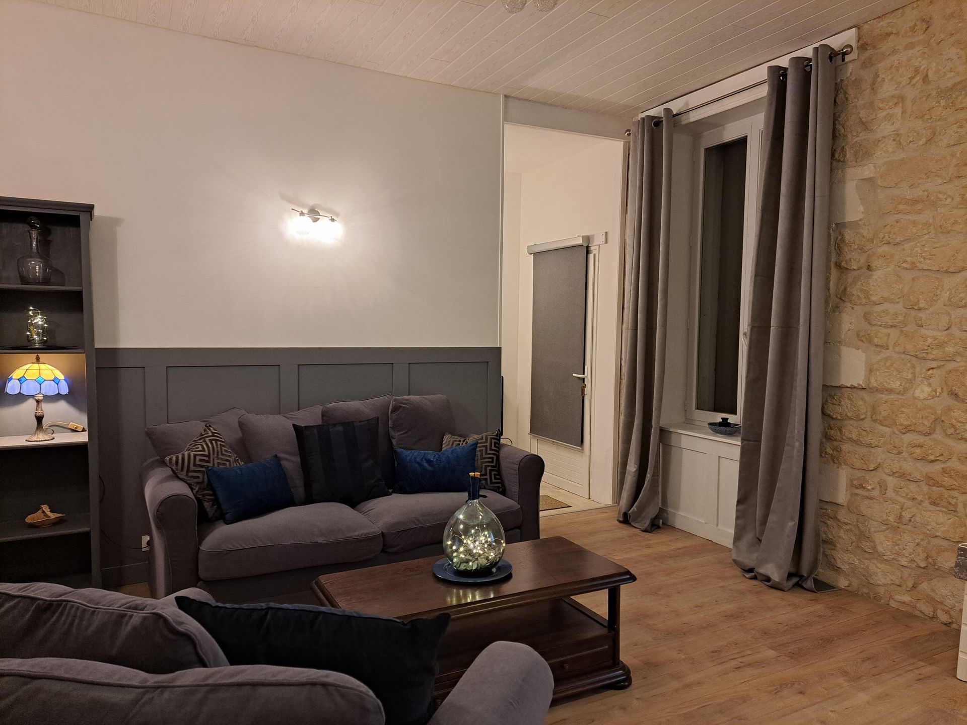 sitting room after renovation with new flooring, grey wainscotting, white walls, grey sofas and curtains