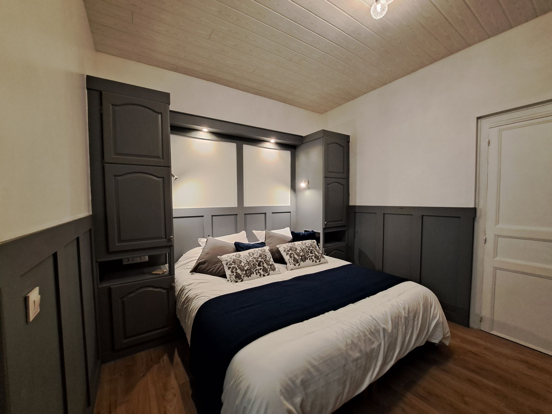 king sized bed with white bedlinen , grey and blue cushions and a blue runner