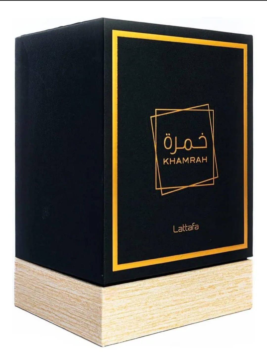 Caja de perfume negra con detalles dorados y escritura árabe, sobre una base de madera clara.