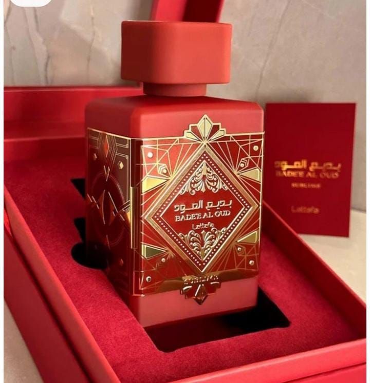 Frasco de perfume rojo con diseño geométrico dorado en una caja de regalo de terciopelo rojo.