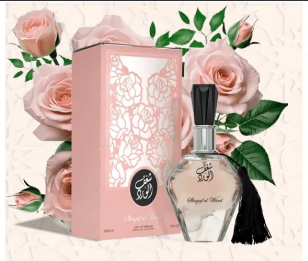 Caja y frasco de perfume rosa con estampado floral y borla negra, rodeados de rosas y hojas verdes.