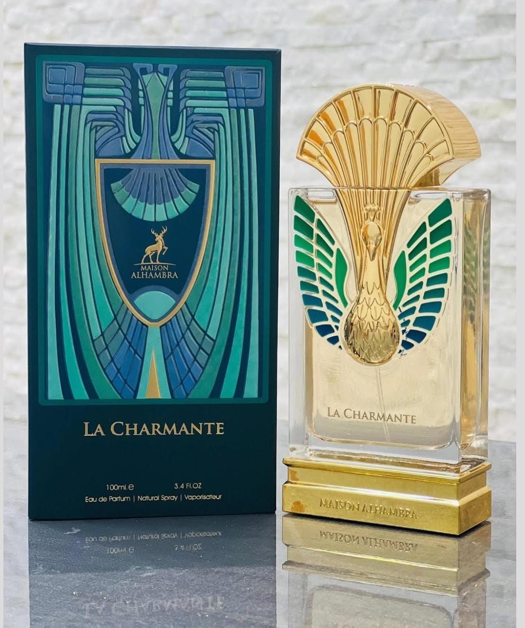 Frasco y caja de perfume de lujo con la etiqueta “La Charmante” en color verde azulado, dorado y crema.