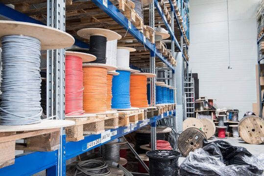 Warehouse aisle with stacked spools of cable and industrial reels on shelves and floor