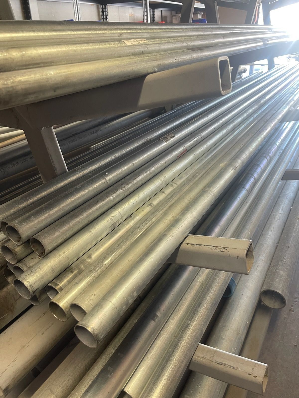 Stacks of silver metal pipes stored on industrial racks in a warehouse