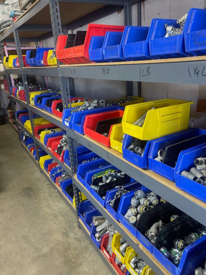 Shelves of blue, red, and yellow plastic bins holding small parts in a workshop or warehouse.