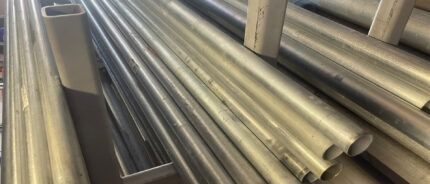 Stacked shiny metal pipes and rectangular steel tubes in a warehouse