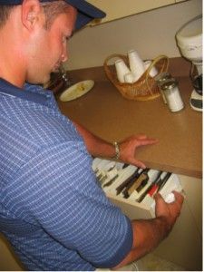 Man in blue shirt repairs a keyboard, with coffee supplies on counter.