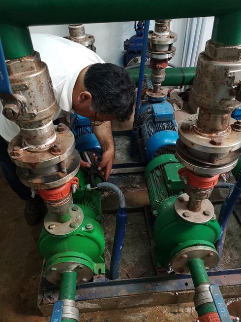 Sistema de bombeo industrial de acero inoxidable con motor eléctrico instalado en un cuarto de servicio con paredes de hormigón.