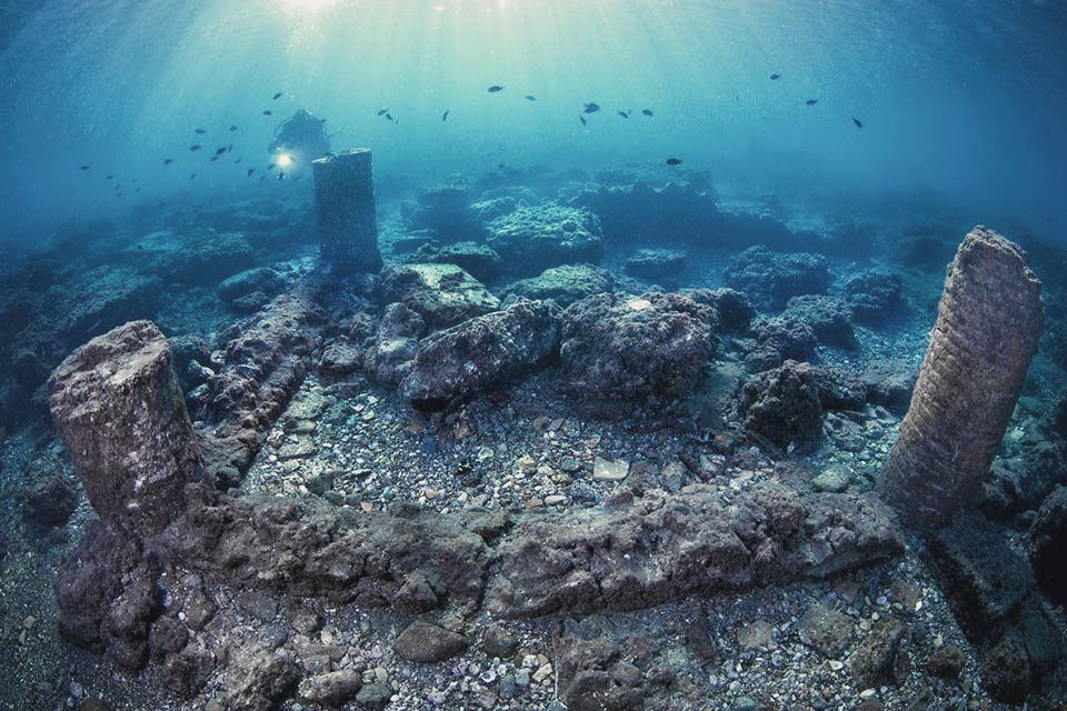 Underwater ruins with stone pillars and a blue, murky seabed