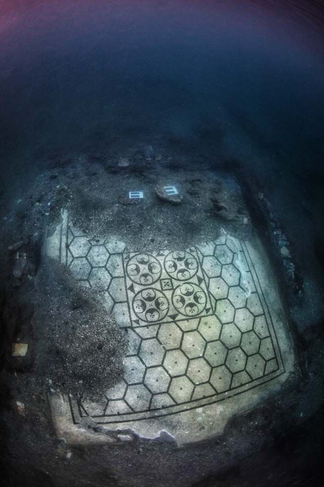 Hexagonal tile floor seen through a dark circular opening, with two small blue lights near the top.