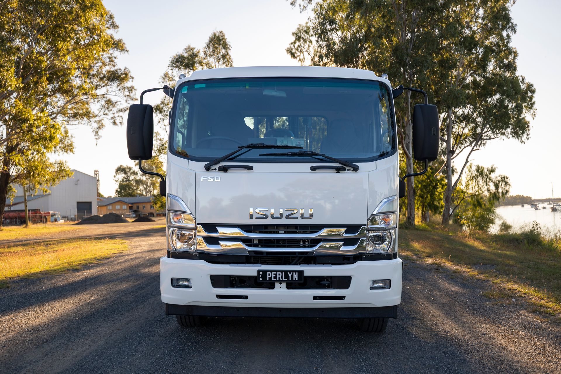White Isuzu truck parked on a road, facing the camera, with trees and a body of water in the background.— Perlyn Towing in Emerald, QLD