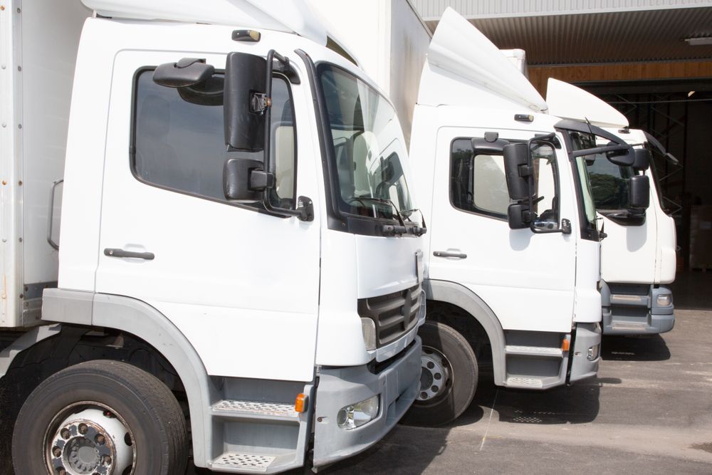 Three White Trucks Are Parked in a Row in Front of a Building — Perlyn Towing in Rockhampton City, QLD