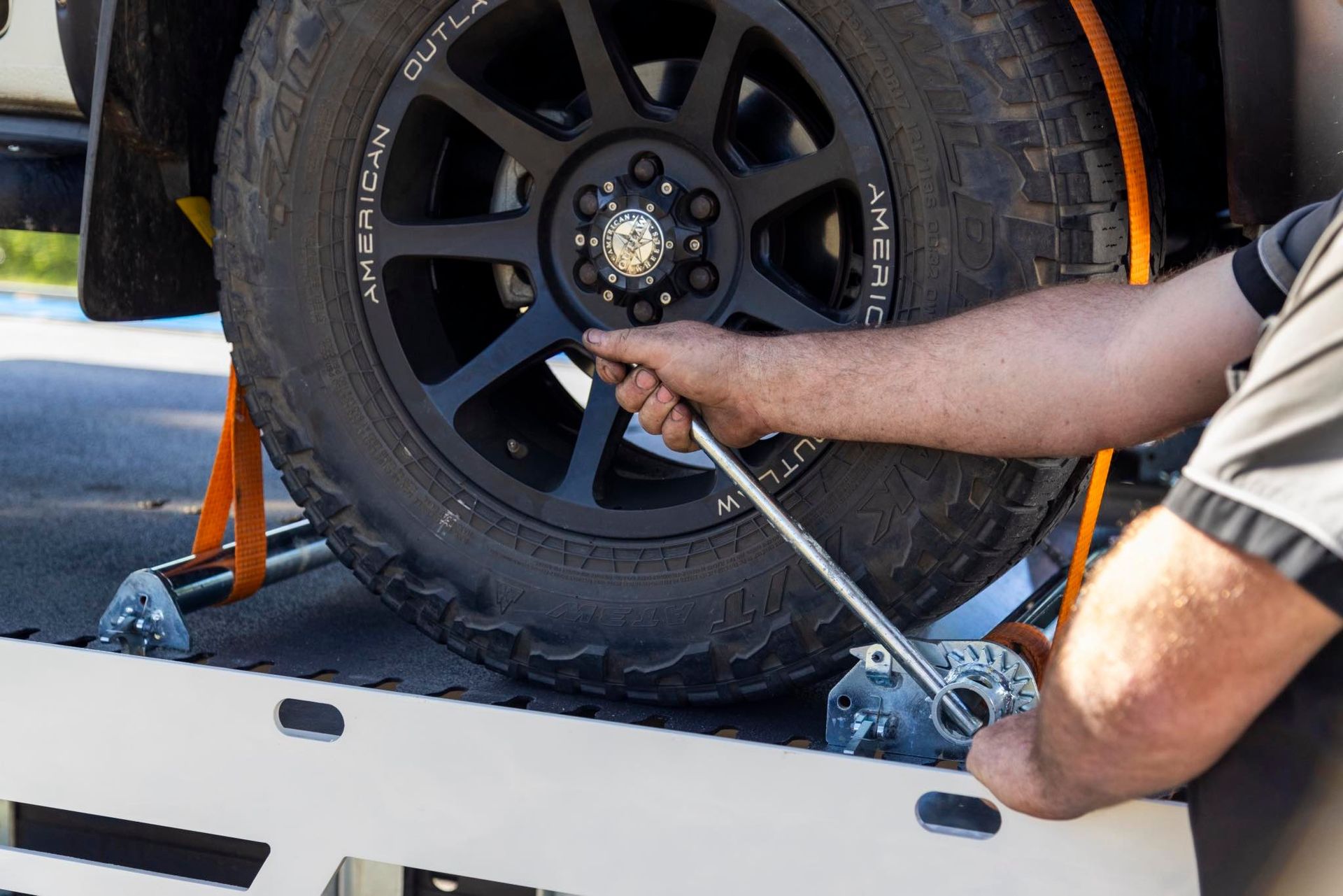 Person using a wrench on a car wheel, on a platform.— Perlyn Towing  in Gladstone, QLD