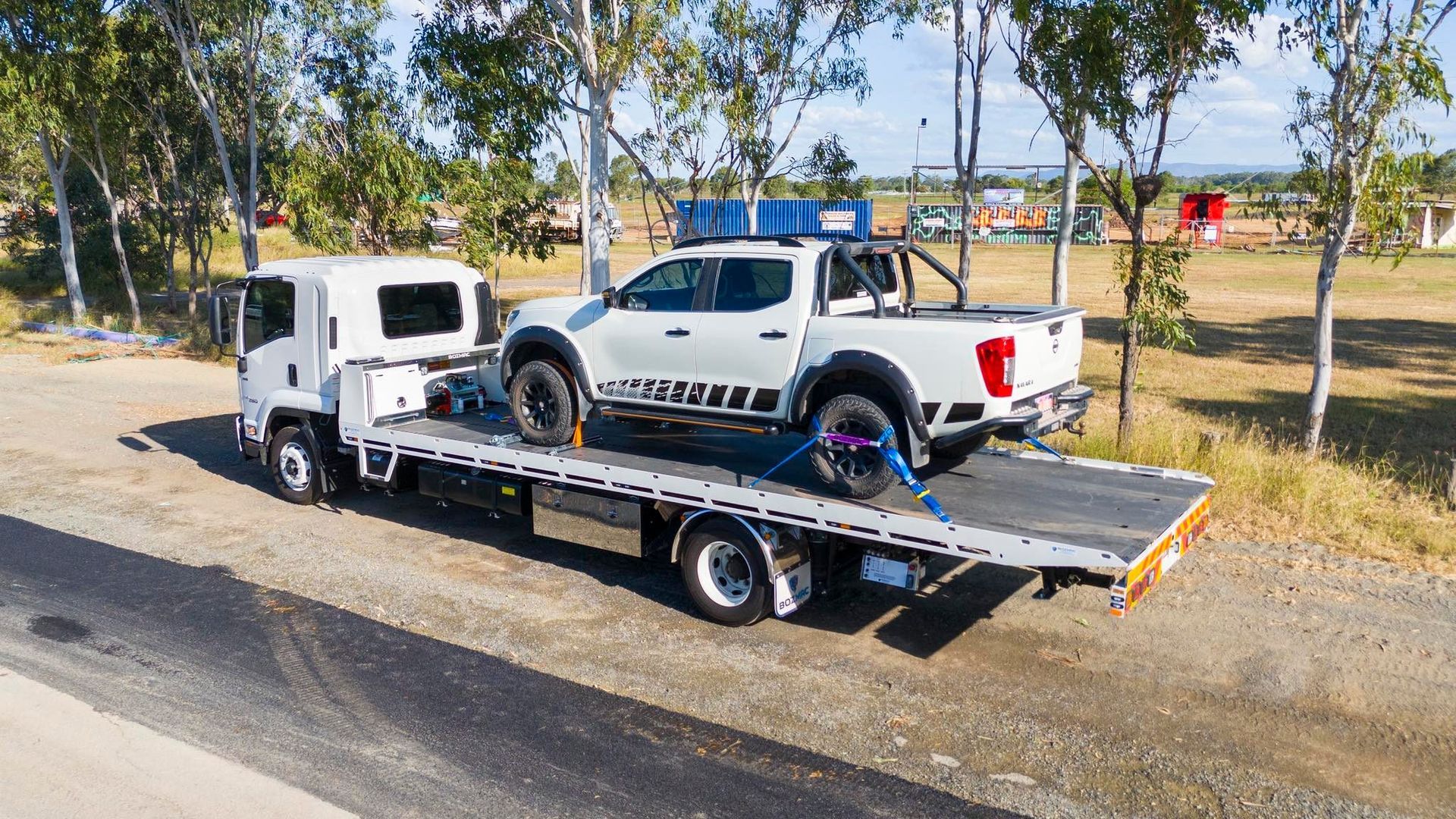 White pickup truck secured on a flatbed tow truck on a road, sunny day. — Perlyn Towing in Rockhampton City, QLD