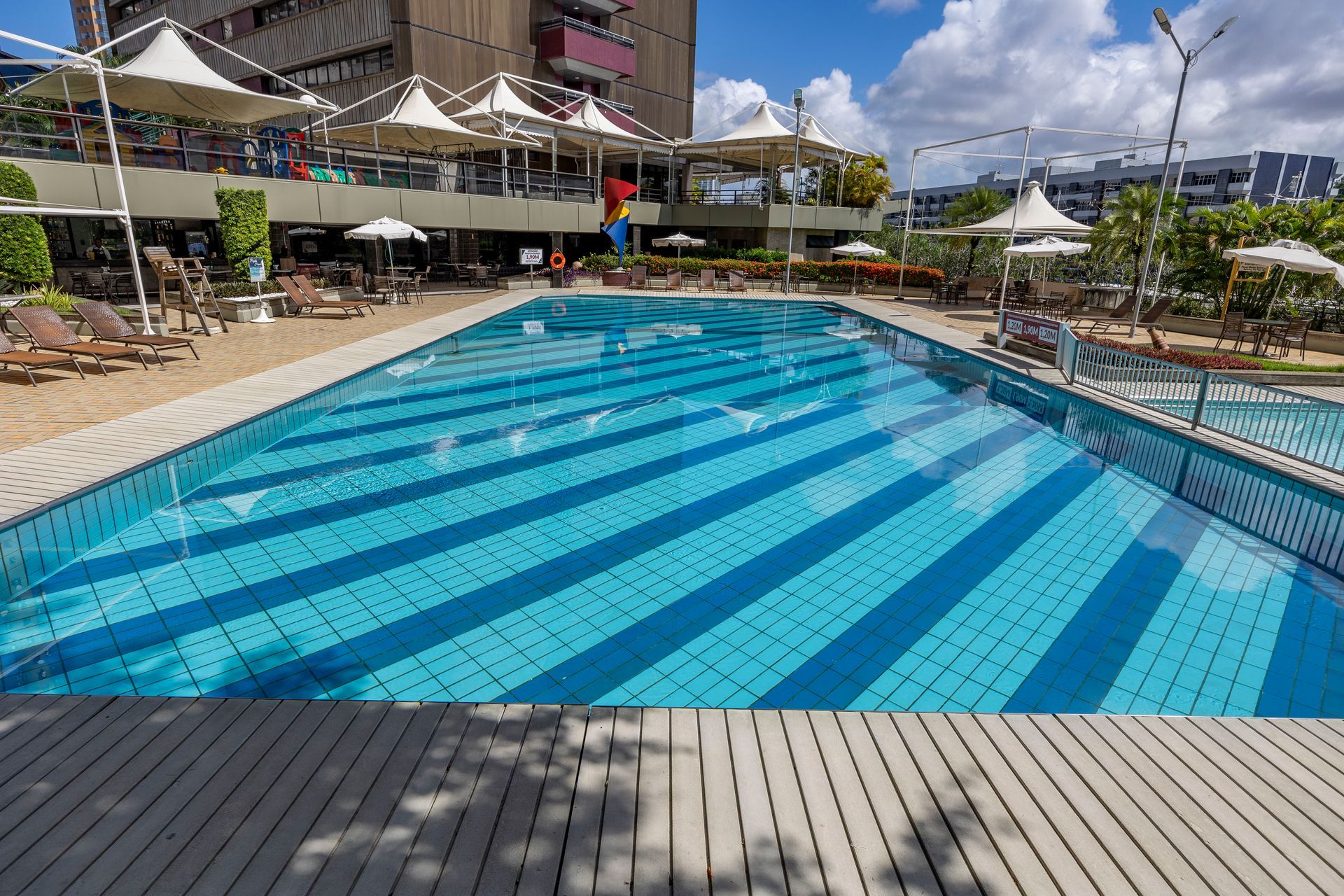 Uma grande piscina com guarda-sóis e cadeiras ao redor