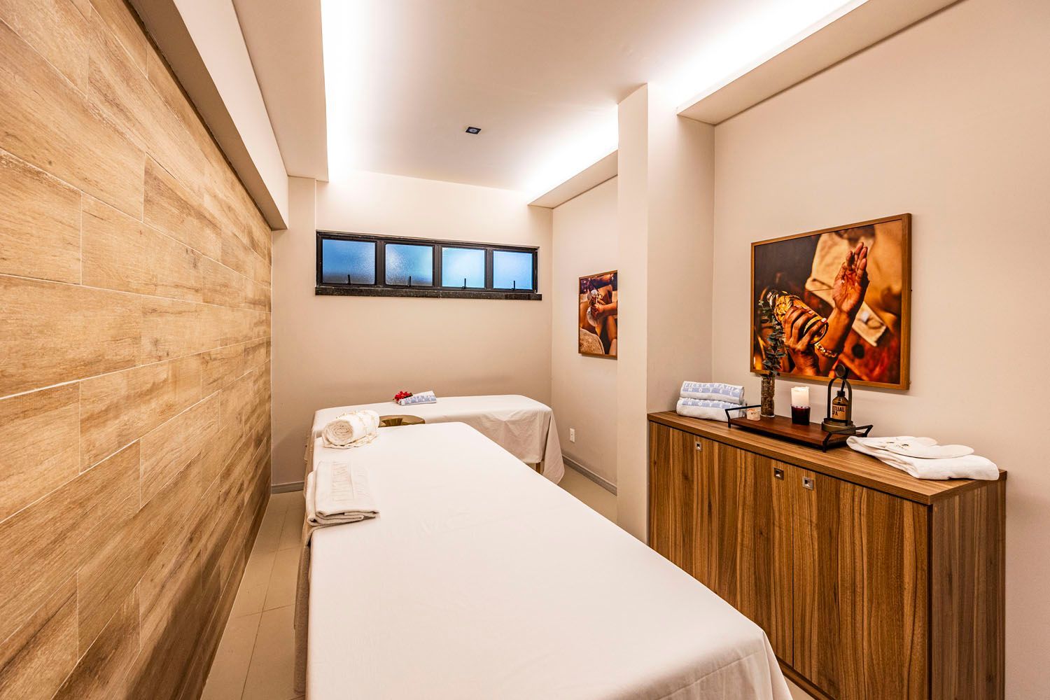Uma sala com duas mesas de massagem e um armário de madeira.