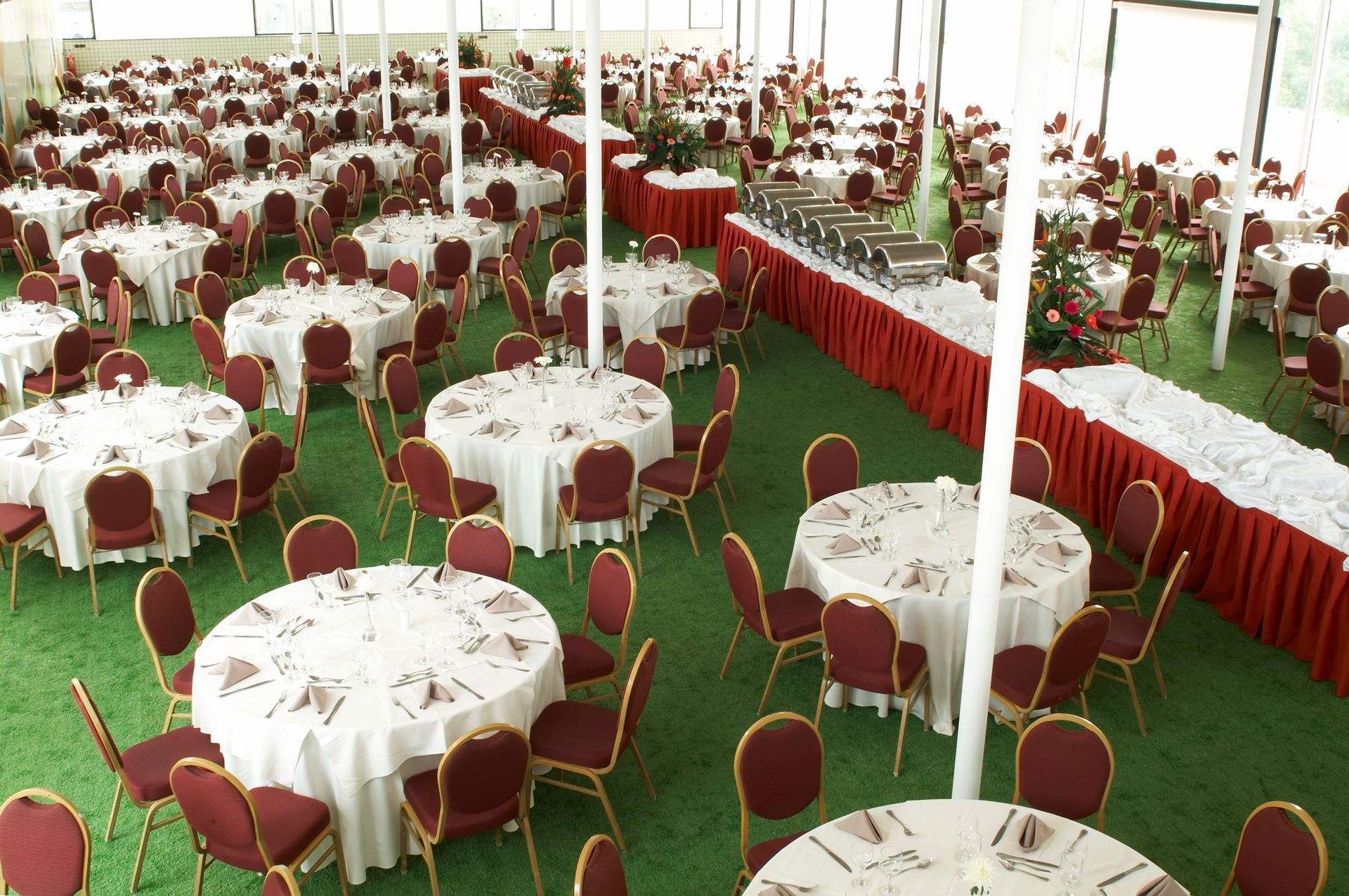 Uma sala grande com mesas e cadeiras preparadas para uma festa