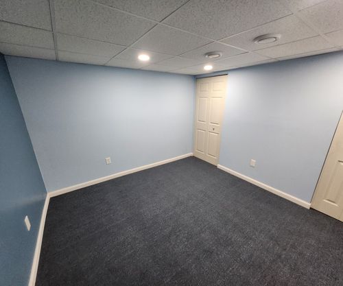 Basement room under construction; drywall on walls and ceiling, unfinished concrete floor.