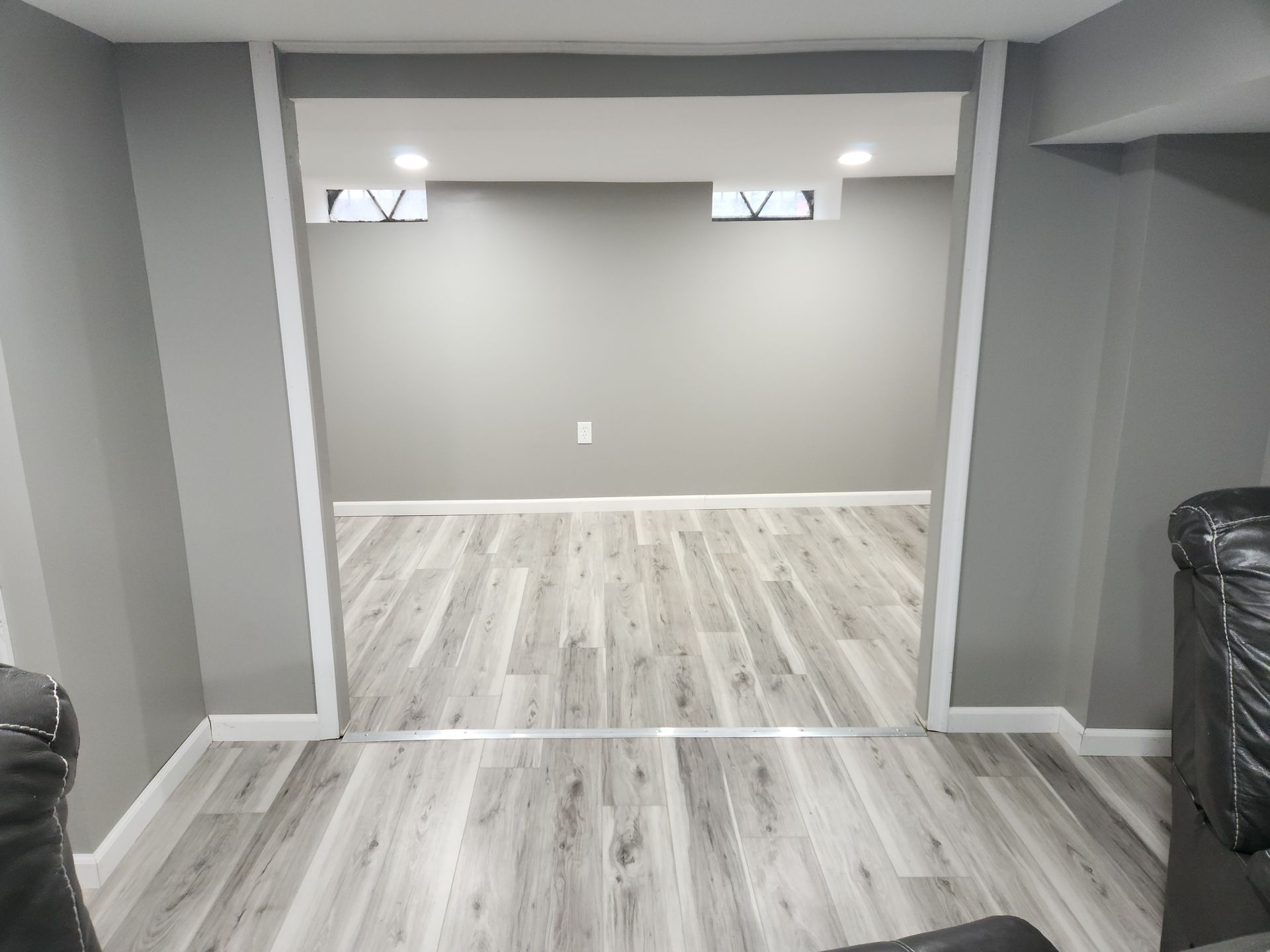 Gray-painted interior, doorway to another room with gray walls and wood-look flooring. White trim frames the opening.