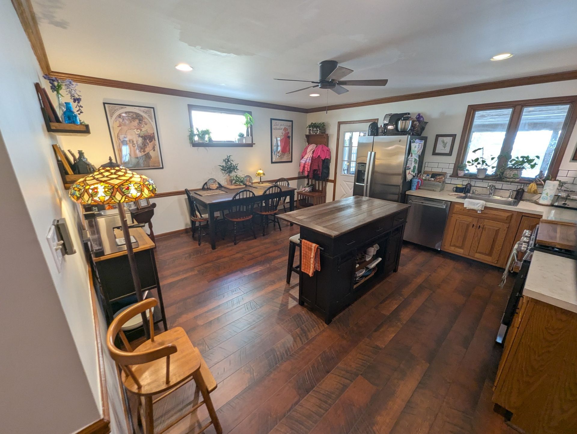 Kitchen with island, dining table, wood cabinets, stainless steel appliances, and wood floor.