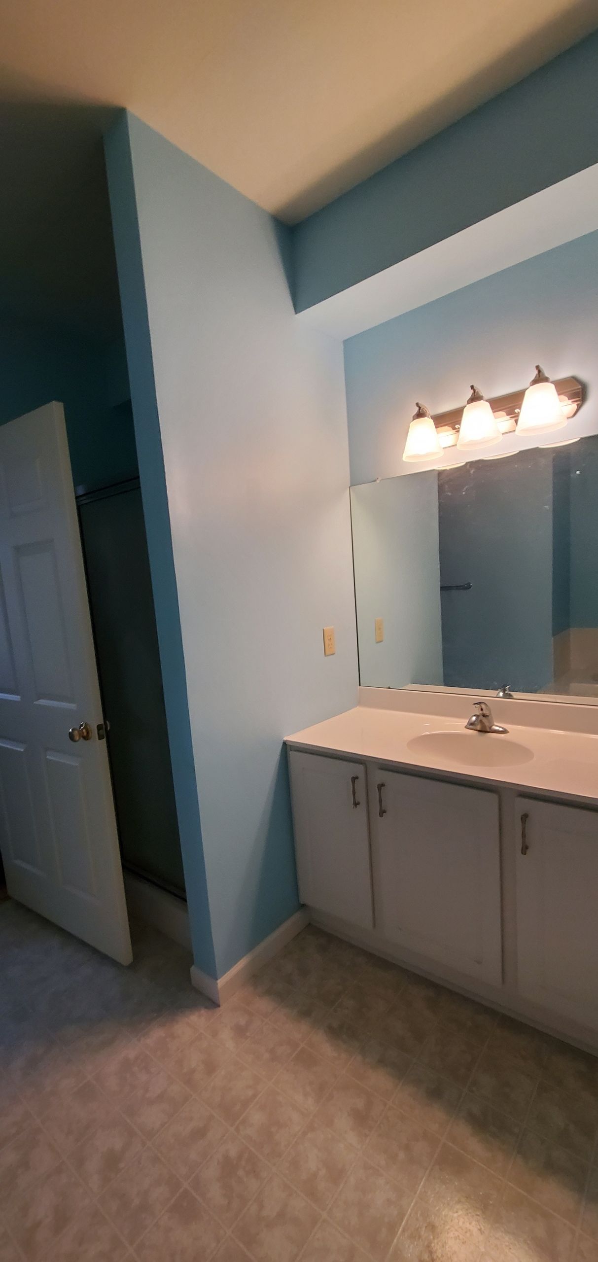 Bathroom with light blue walls, white vanity, and a mirror.