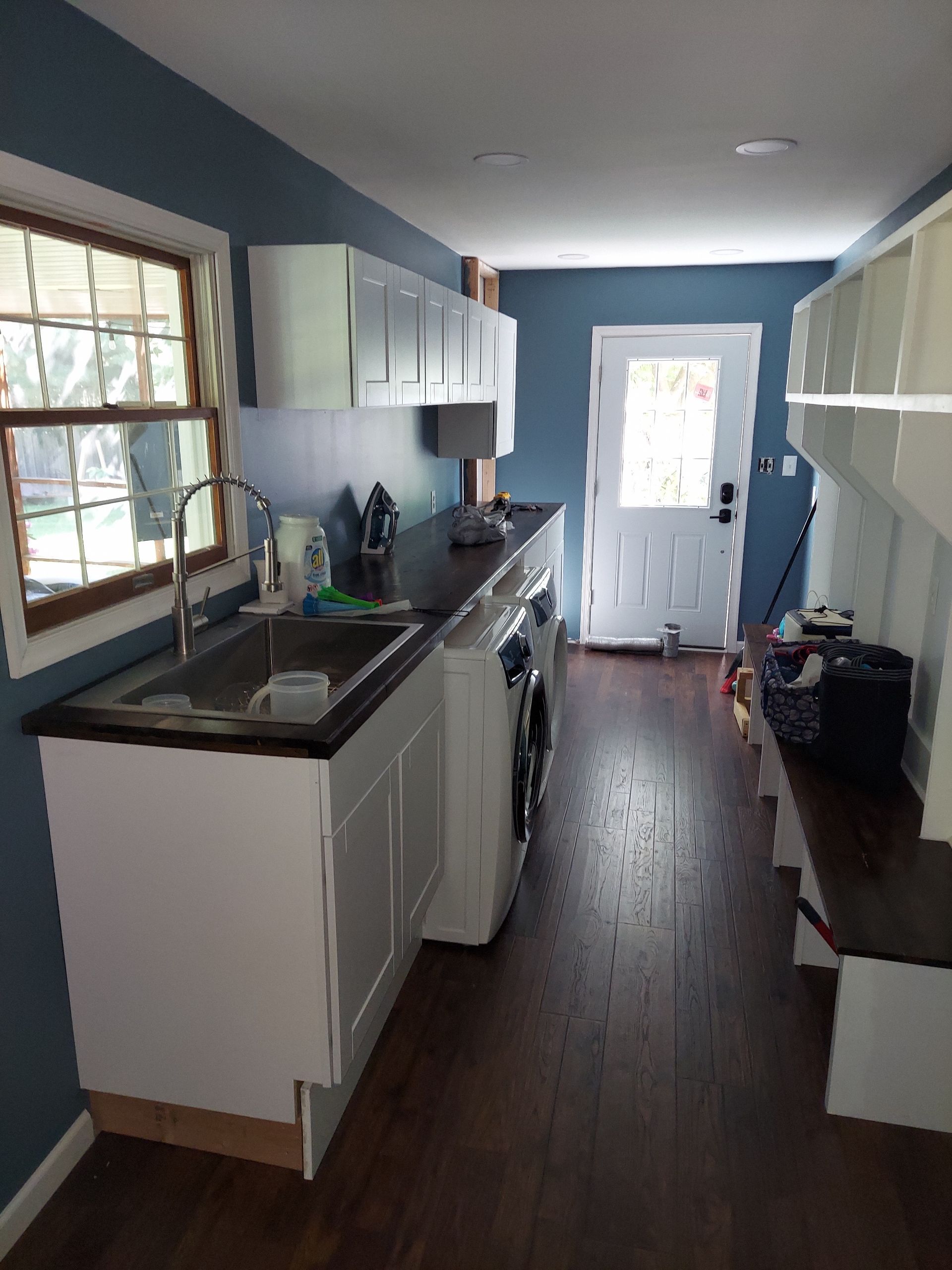 Laundry room with white cabinets, dark countertop, blue walls, a sink, and a washer.