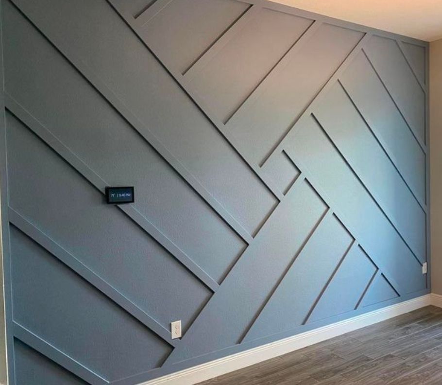 Gray accent wall with angled wood slats and a small black wall sign in a modern room.