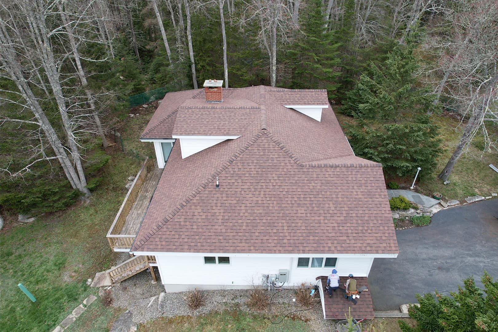 An aerial view of a house with a red roof in the middle of a forest.