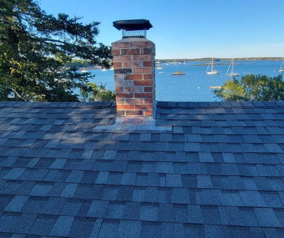 A chimney on top of a roof overlooking a body of water