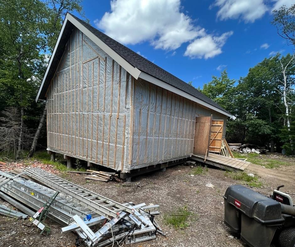 A small wooden building is being built in the woods.