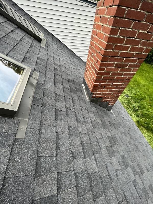 A roof with a skylight and a chimney on it.
