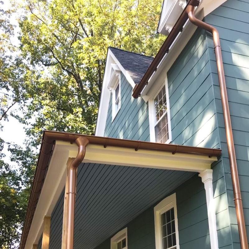 A blue house with copper gutters and a porch
