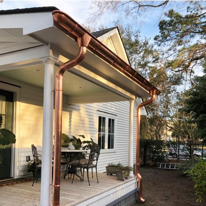 A white house with a copper gutter on the porch