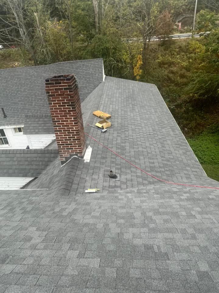 A roof with a chimney and a brick chimney on it.