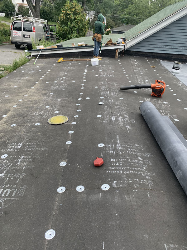 A man is standing on the roof of a house.