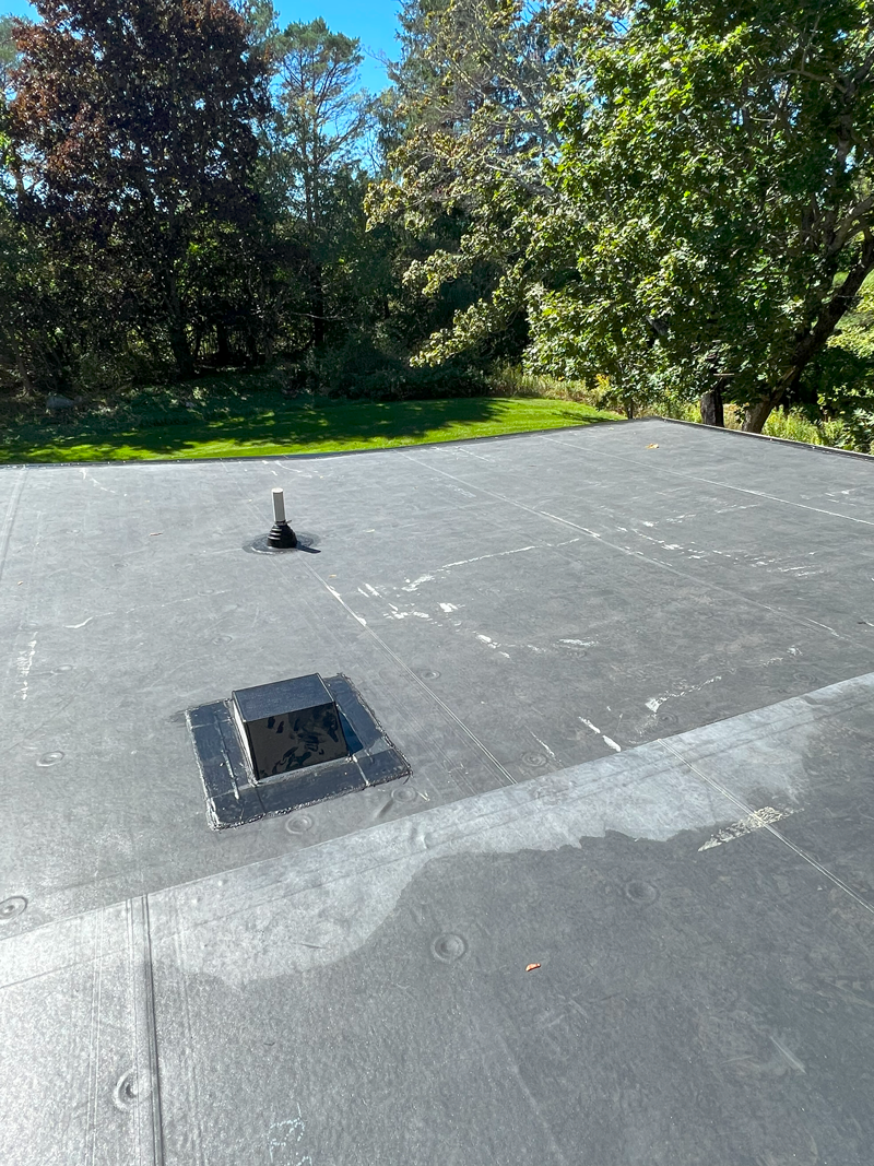 A roof with a hole in it and trees in the background.