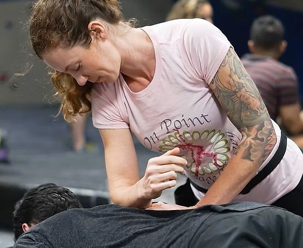 Woman in a pink shirt giving a back massage on a gym floor