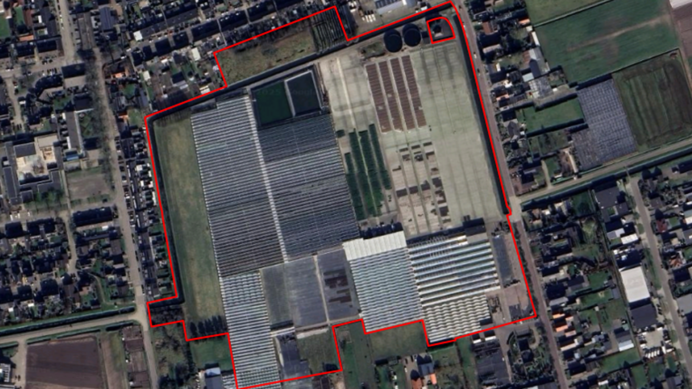 Luchtfoto van een groot kassencomplex, omgeven door wegen, huizen en landbouwgrond.