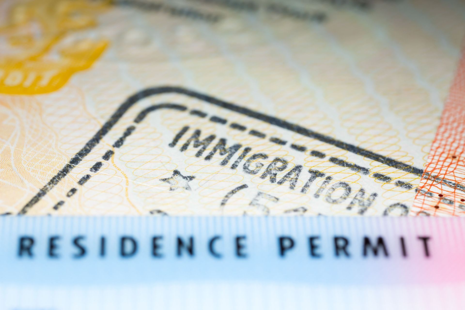 Close-up of a residence permit document with blue text and an immigration stamp in the background
