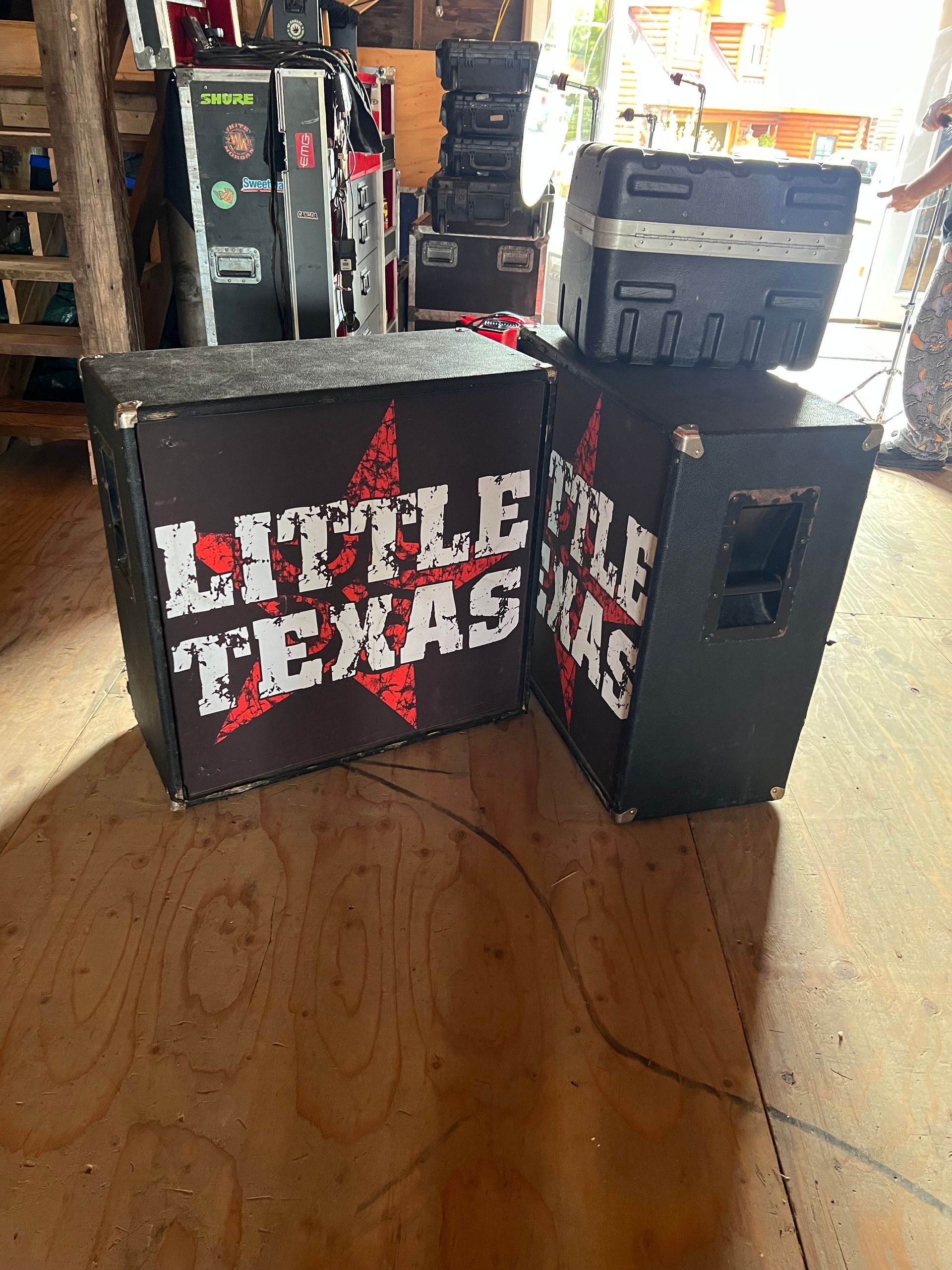 Black speakers and cases with “Little Texas” text in a warehouse or storage area