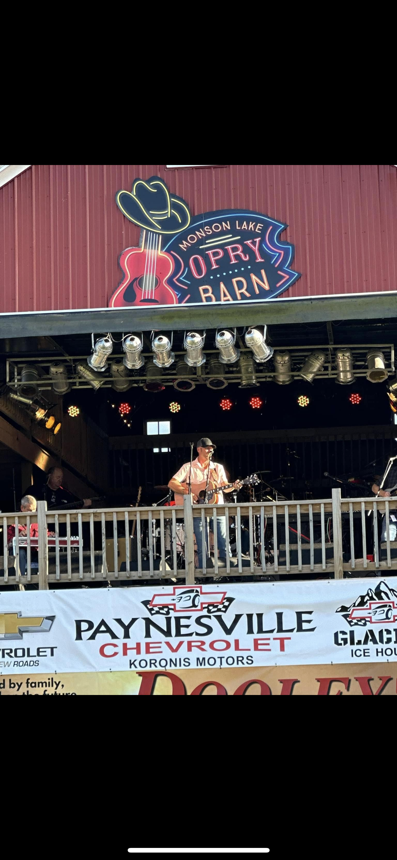 Outdoor stage at Painesville City with a red barn-style backdrop and a singer performing under lights