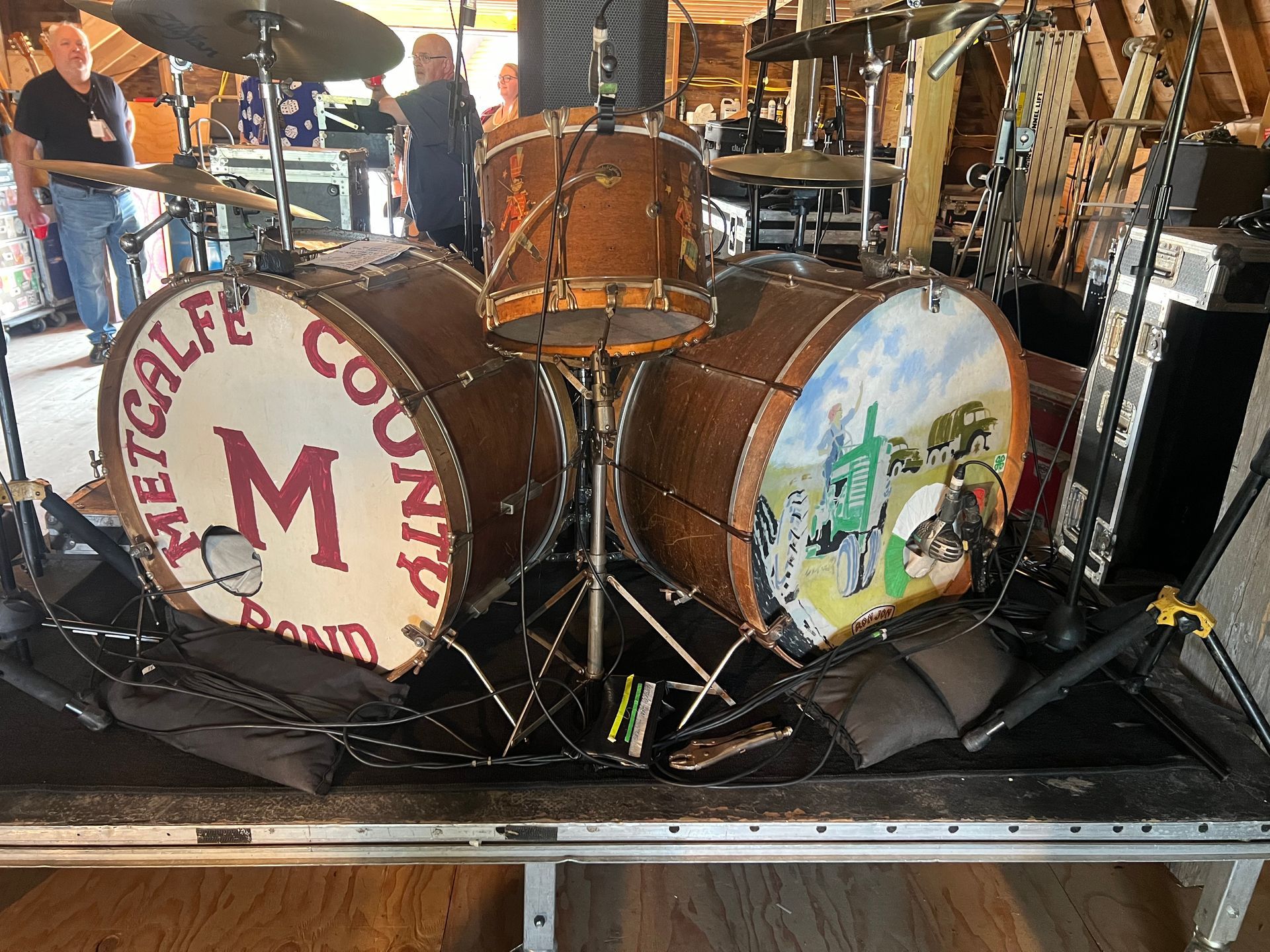 Two large bass drums on a stage, one labeled “Celtic Country” with a red M, the other with a painted scene.